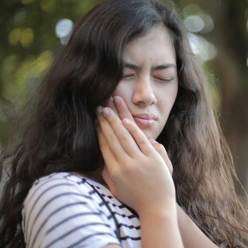Woman experiencing tooth pain needing emergency dental care